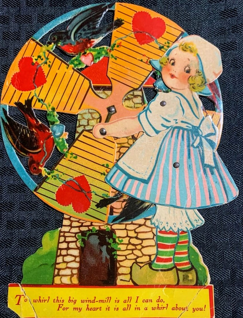 Vintage Valentine card with girl in blue dress next to windmill surrounded by red hearts