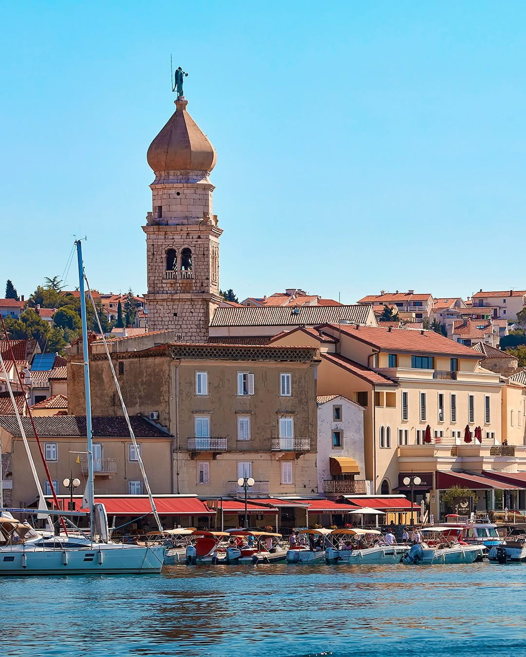 Historic waterfront of Krk town with bell tower and boats in harbor