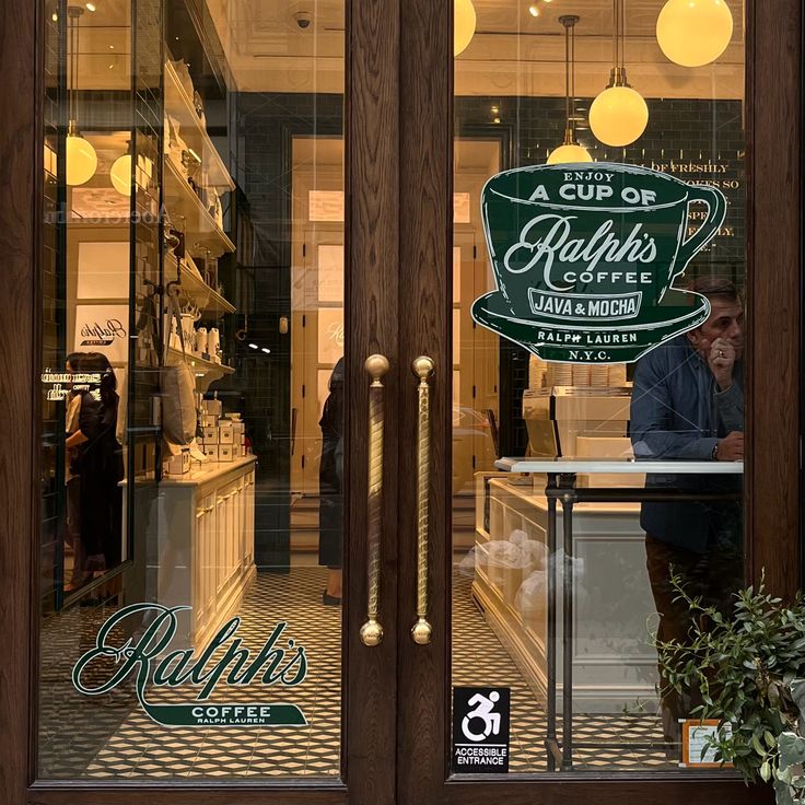 Glass entrance doors of Ralph's Coffee cafe with warm lights inside