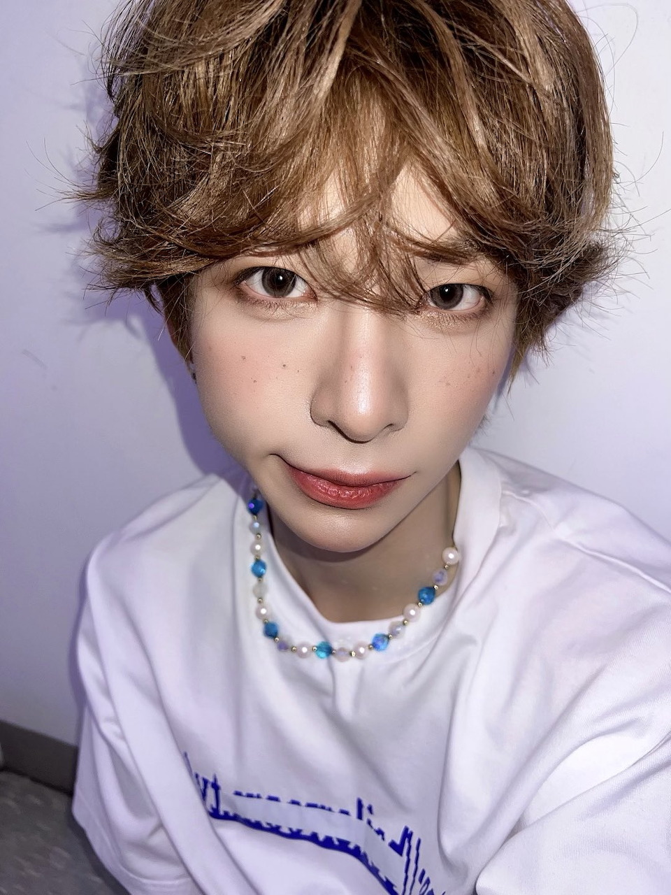 Portrait of young person with brown hair in white t-shirt and beaded necklace