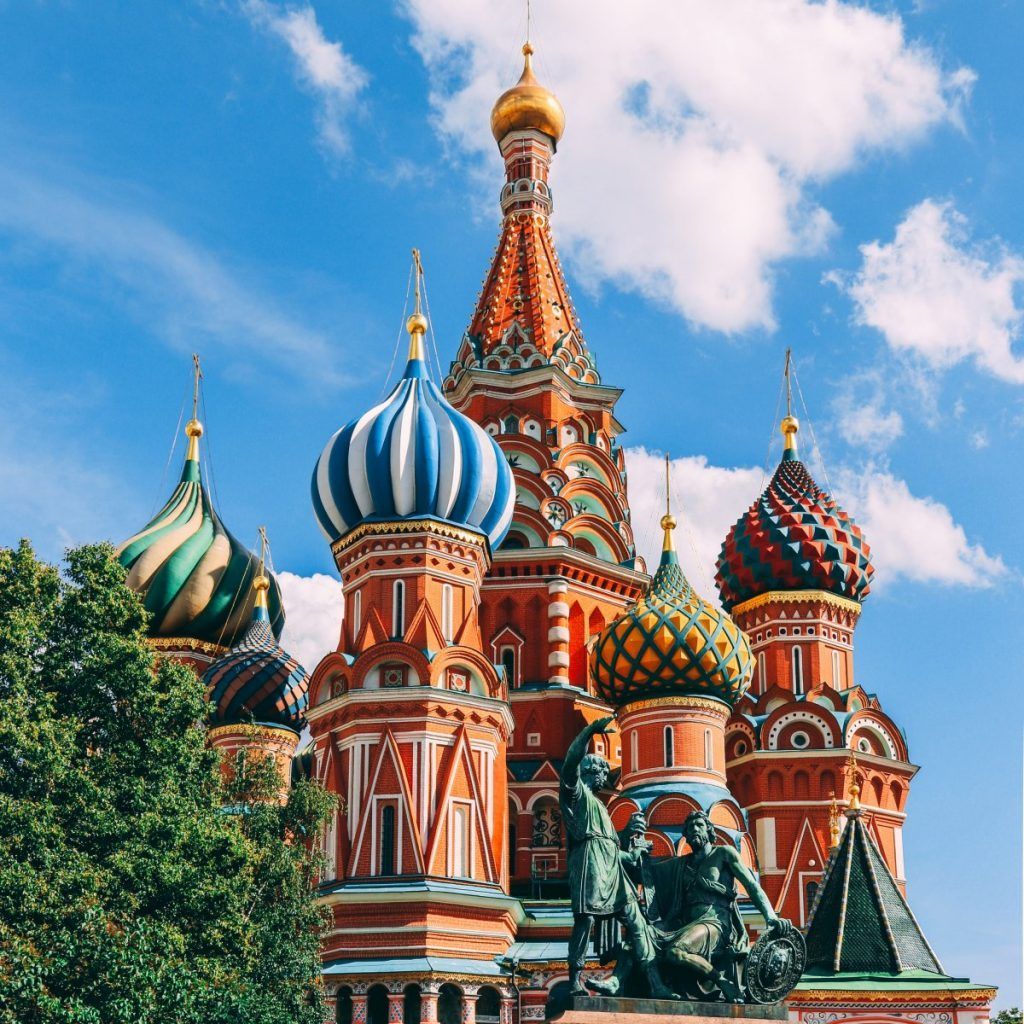St. Basil's Cathedral with colorful onion domes and a statue in front under a blue sky