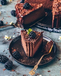 Chocolate cake slices topped with blackberries on plates with scattered berries and crumbs