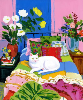 White cat lying on a colorful patterned bed surrounded by potted plants and flowers in a bright room