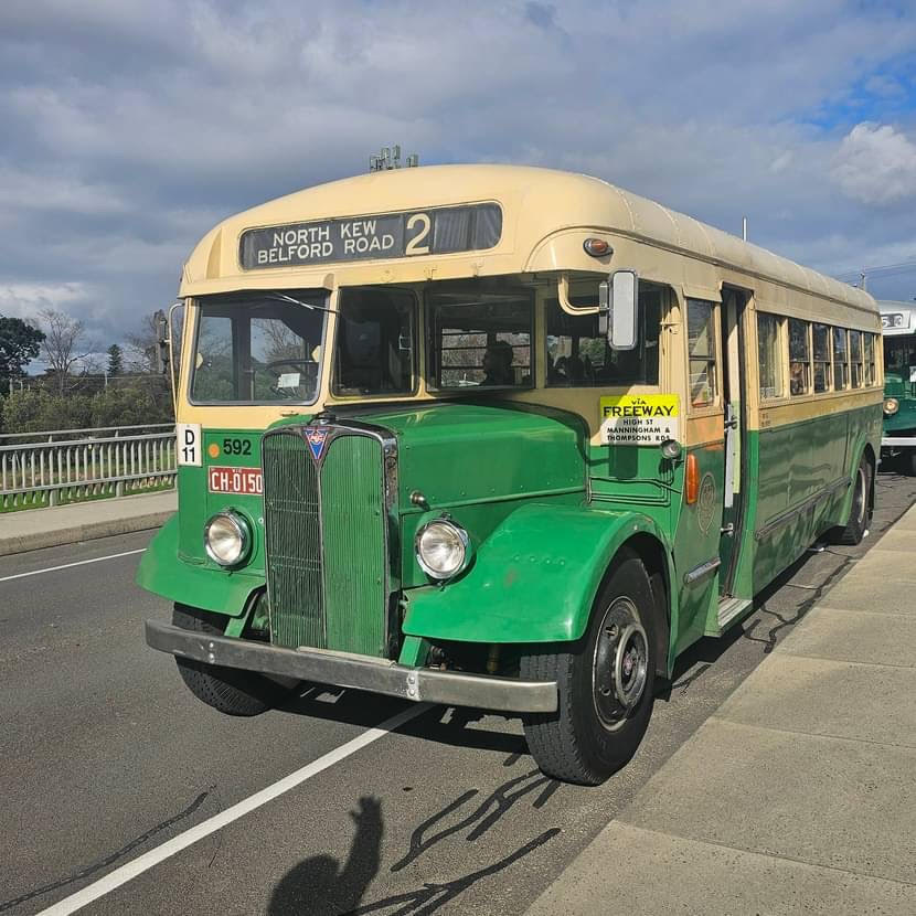 Vintage green and cream bus parked beside a road under a cloudy sky