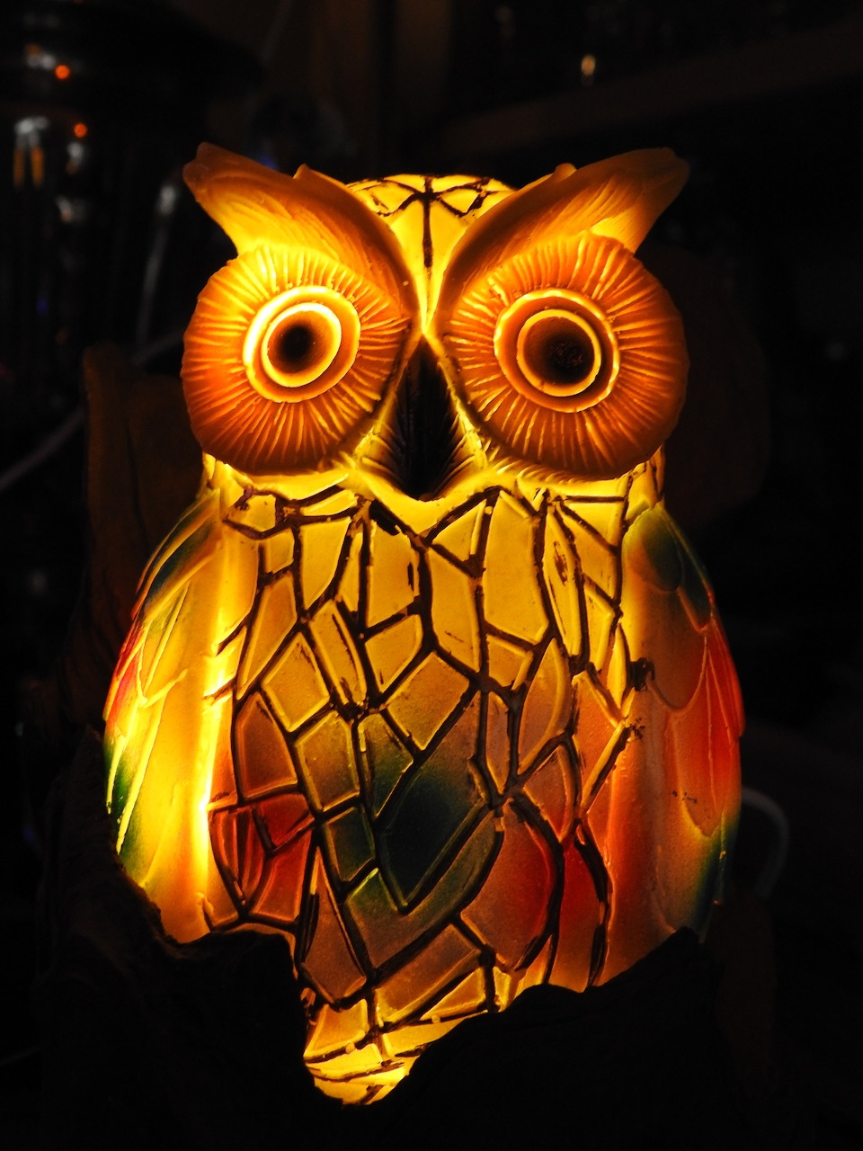 Illuminated decorative owl lantern glowing in warm gold and amber tones against a dark background