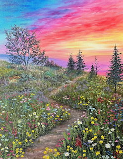 Colorful sunset sky over a hillside meadow filled with wildflowers, evergreens, and a dirt path