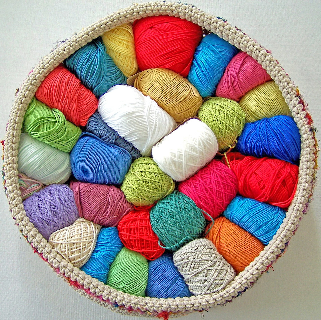 Round woven basket filled with colorful yarn balls viewed from above