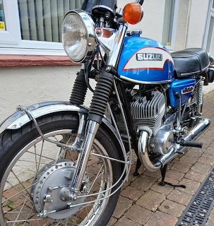 Blue and white 1972 Suzuki T500 classic motorcycle parked on pavement