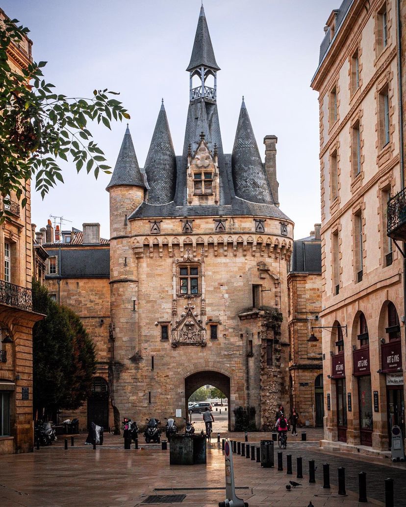 Historic stone gate tower with pointed turrets between old buildings in Bordeaux