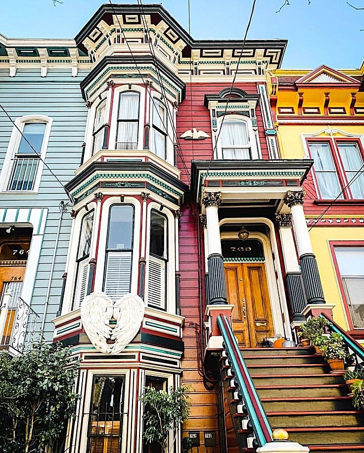 Ornate Victorian row houses with bay windows in pastel blue, pink, and yellow colors lined up on a San Francisco street