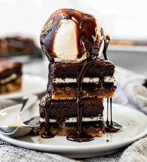 Stack of chocolate brownies with vanilla ice cream and chocolate syrup drizzle