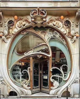 Ornate Art Nouveau entrance with curved archway, sculptural decorations, and elegant door with flowing organic lines