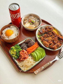 Tray of Korean food with fried chicken, rice and egg, soup, vegetables, and a red soda can