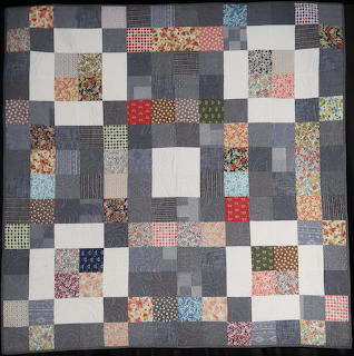 Patchwork quilt with denim and floral fabric squares in blue, cream, and multicolor prints