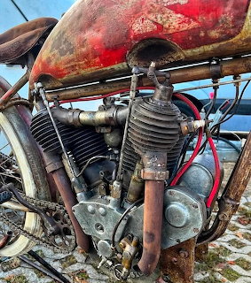 Weathered vintage V-twin motorcycle engine with rusty red tank and exposed mechanics