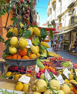 Colorful fruit stand with hanging lemons and oranges on a sunny street in Sorrento, Italy