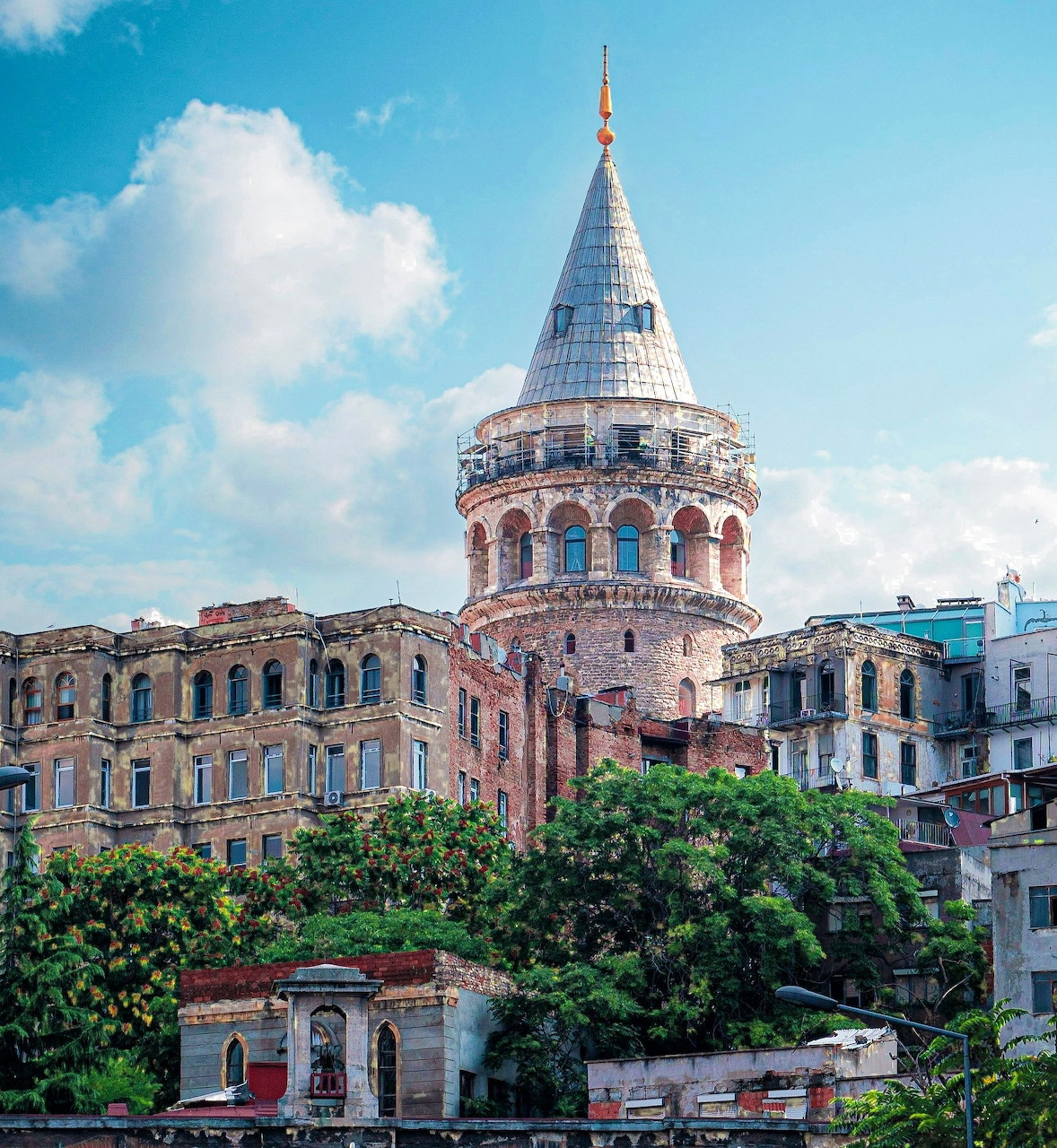 Galata Tower above historic buildings and trees in Istanbul under a blue sky