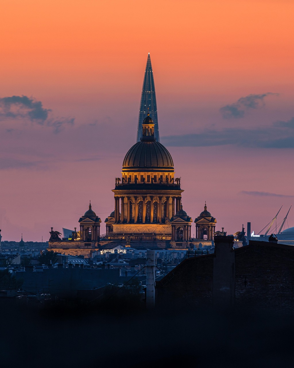 Saint Isaac's Cathedral with golden dome silhouetted against a bright orange sunset sky in Saint Petersburg
