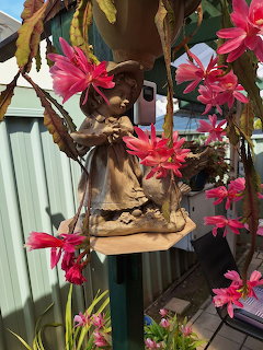 Angel statue with pink flowers in garden
