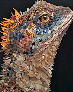 Mosaic iguana head made of colorful stone pieces with orange crest and detailed eye against dark background