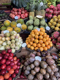 Colorful tropical fruit market display with pineapples, dragon fruit, oranges, and various exotic fruits in baskets