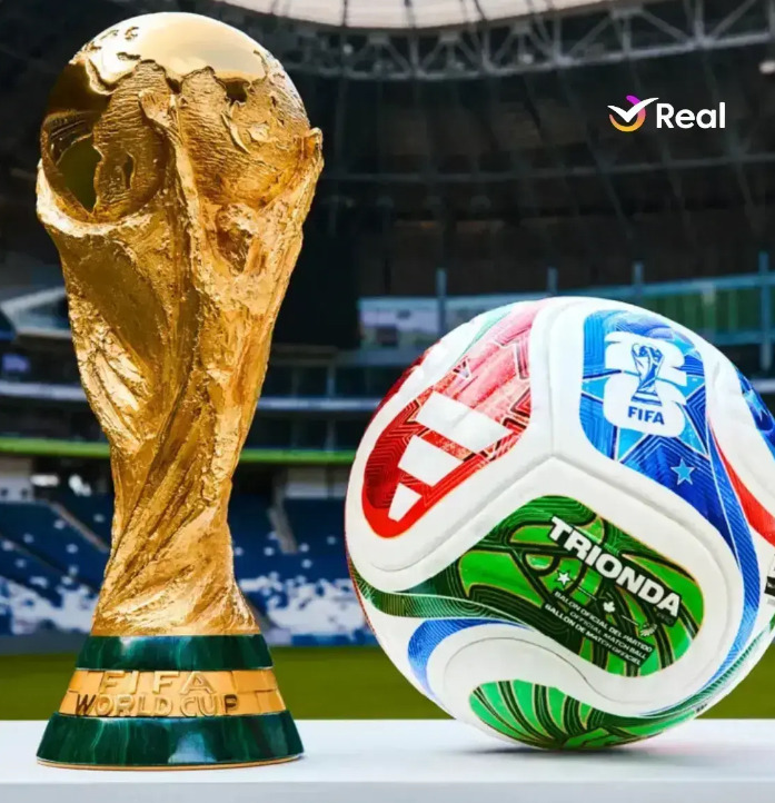 Golden World Cup trophy next to a colorful soccer ball in a stadium