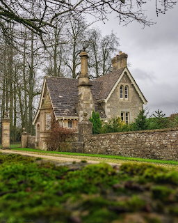 Stone cottage behind a low wall with bare trees and cloudy sky