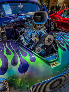 Custom hot rod with exposed supercharged engine and purple-green flame paint