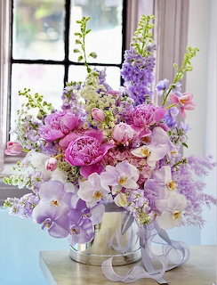 Colorful spring flower bouquet with purple and pink blooms in silver vase near window