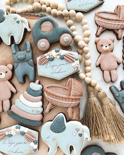 Assortment of pastel pink and blue decorated baby-themed sugar cookies arranged on white surface
