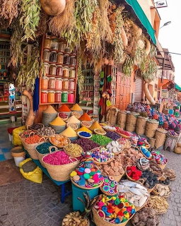 Colorful Moroccan spice market stall with baskets of spices, herbs, and tagine pots