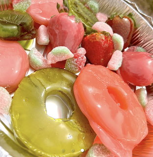Close-up of glossy candied fruit and sugar-coated sweets in pink, green, and red
