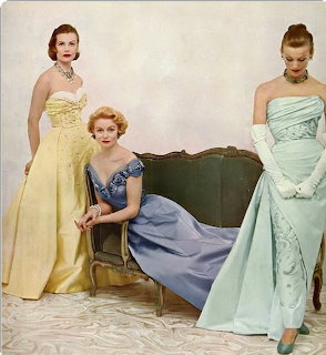 Three women modeling vintage 1950s pastel satin evening gowns in yellow, blue, and mint green