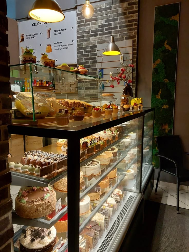 Illuminated bakery display case filled with cakes and pastries in cozy cafe interior