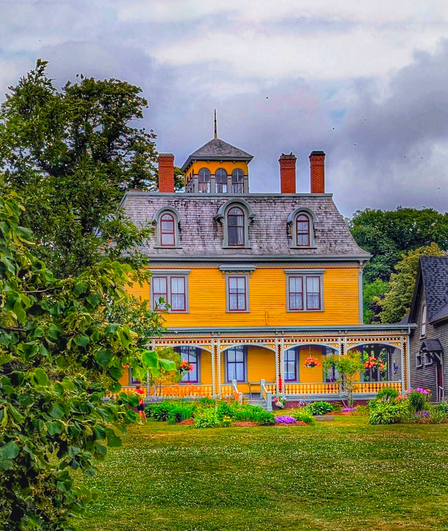Yellow Victorian house with red chimneys and green lawn