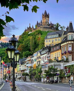 Cochem Castle on hilltop above colorful German town buildings with street lamp in foreground