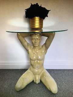 Sculptural table with kneeling male figure base holding glass top and golden bowl