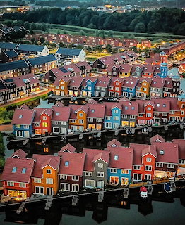 Aerial view of colorful Dutch houses along a canal at dusk in Groningen with reflections in the water