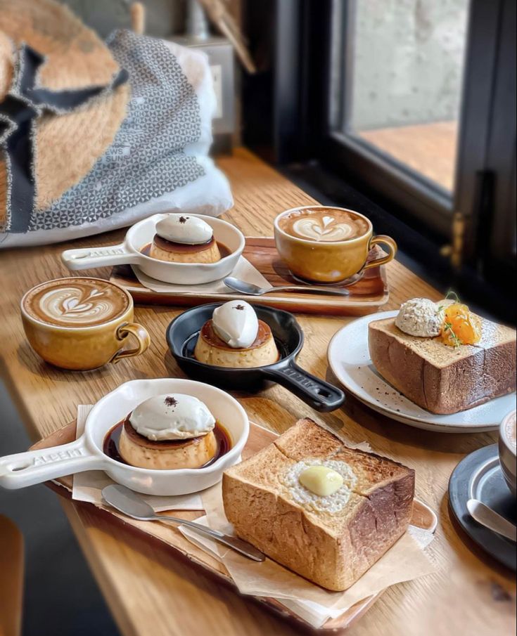 Coffee drinks and desserts on wooden table by window