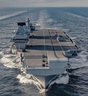 HMS Queen Elizabeth aircraft carrier moving through grey ocean waters seen from elevated front angle
