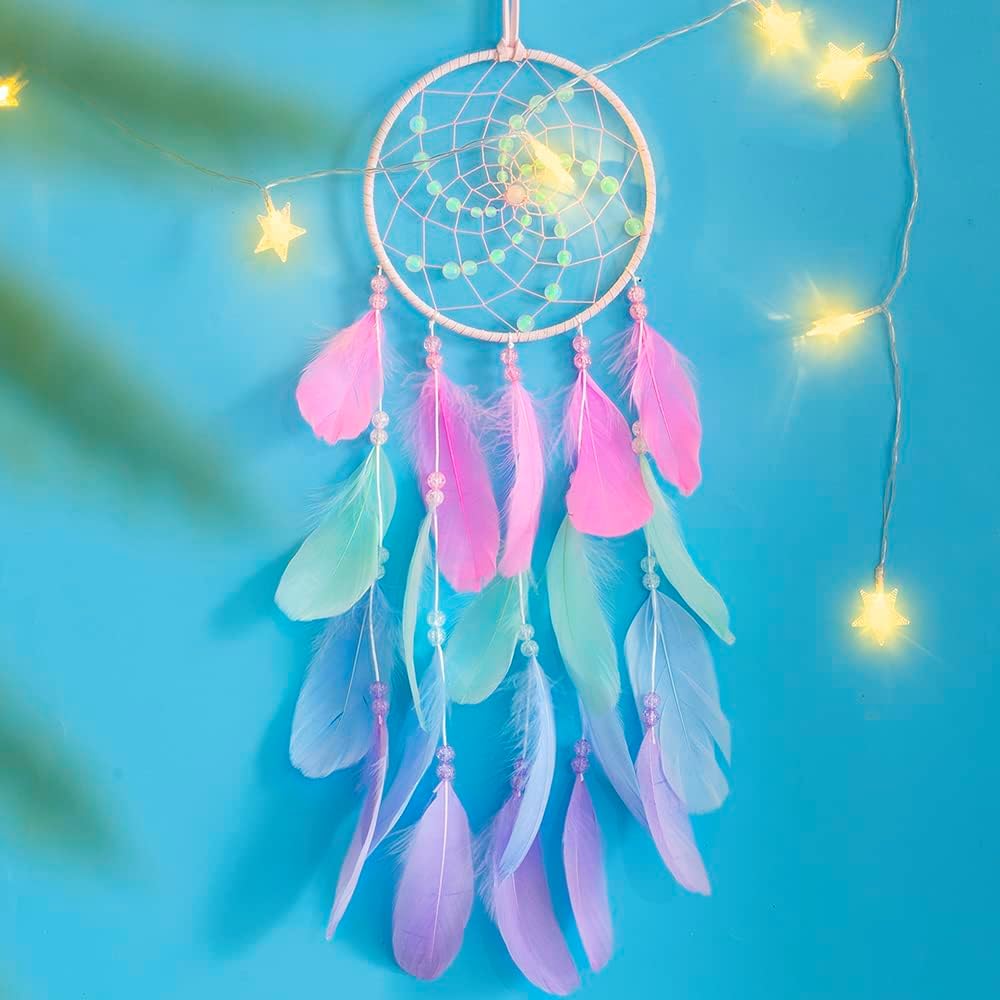 White dreamcatcher with colorful feathers and glowing fairy lights on turquoise background