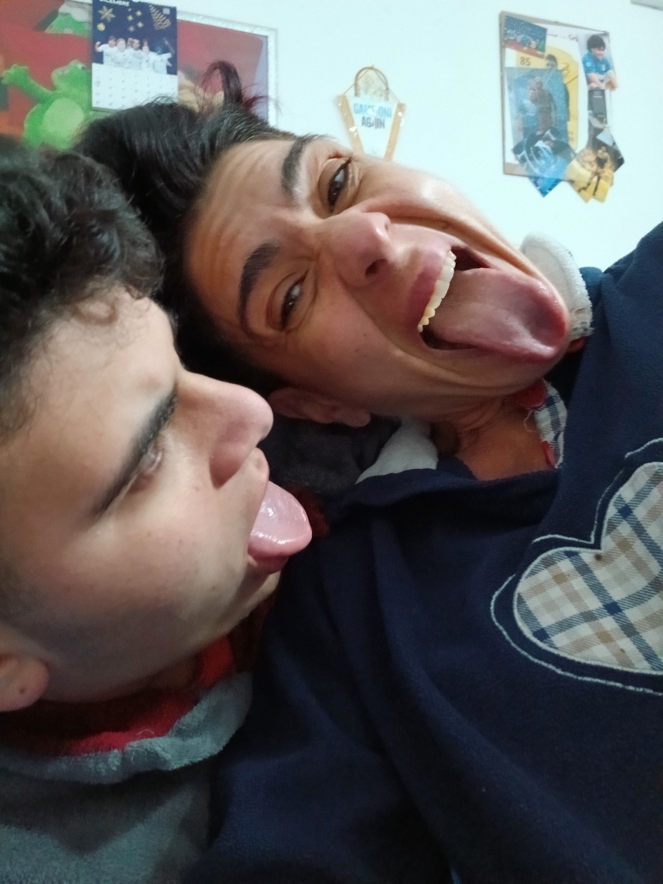 Young man and woman making silly faces with tongues out in a close-up selfie