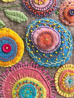 Colorful embroidered circular mandalas with detailed stitching patterns in various colors on fabric background