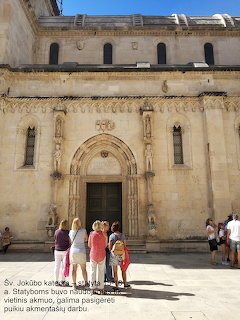 Tourists viewing the stone facade of St James Cathedral in Šibenik, Croatia with arched entrance and carvings