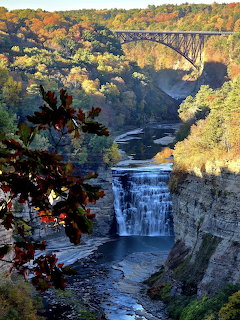 Waterfall flowing through gorge with stone bridge and autumn trees at Letchworth State Park