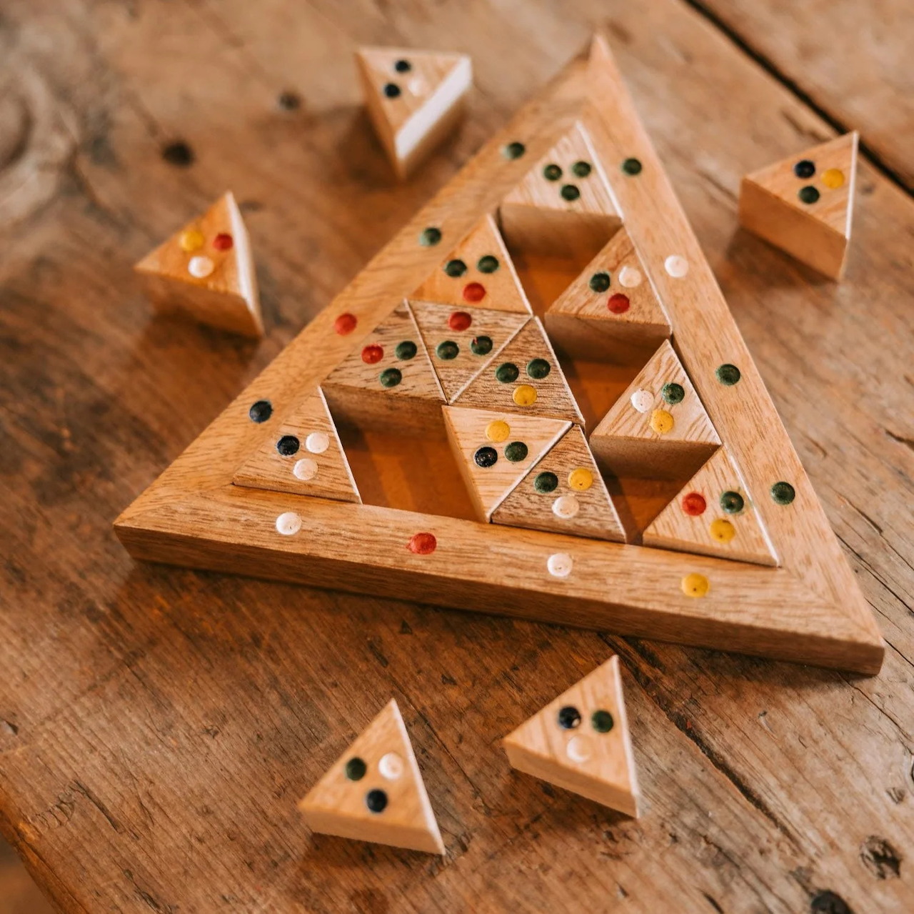 Wooden triangle puzzle pieces in a triangular tray on a wooden tabletop