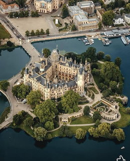 Aerial view of Schwerin Castle on an island surrounded by water with manicured gardens and trees