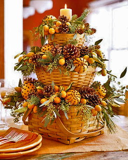 Tiered wicker basket centerpiece with pinecones, berries, greenery, and a candle on a table