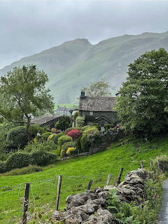 Stone cottage in Lake District valley with green hills and stone walls