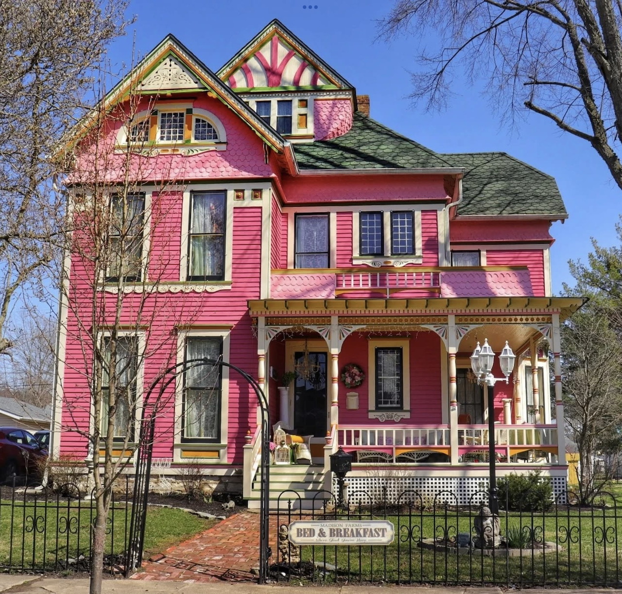 Pink Victorian house with ornate trim, front porch, and a bed and breakfast sign